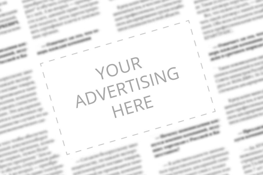Close up of a copy space with wrtitten words Your Advertising Here on a blurred background of a newspaper. Business concept. Adding ad into paper page. Mockup of a newspaper advertisement column